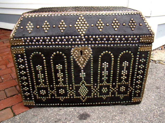 A late 18th or early 19th century brass decorated leather trunk with canted top